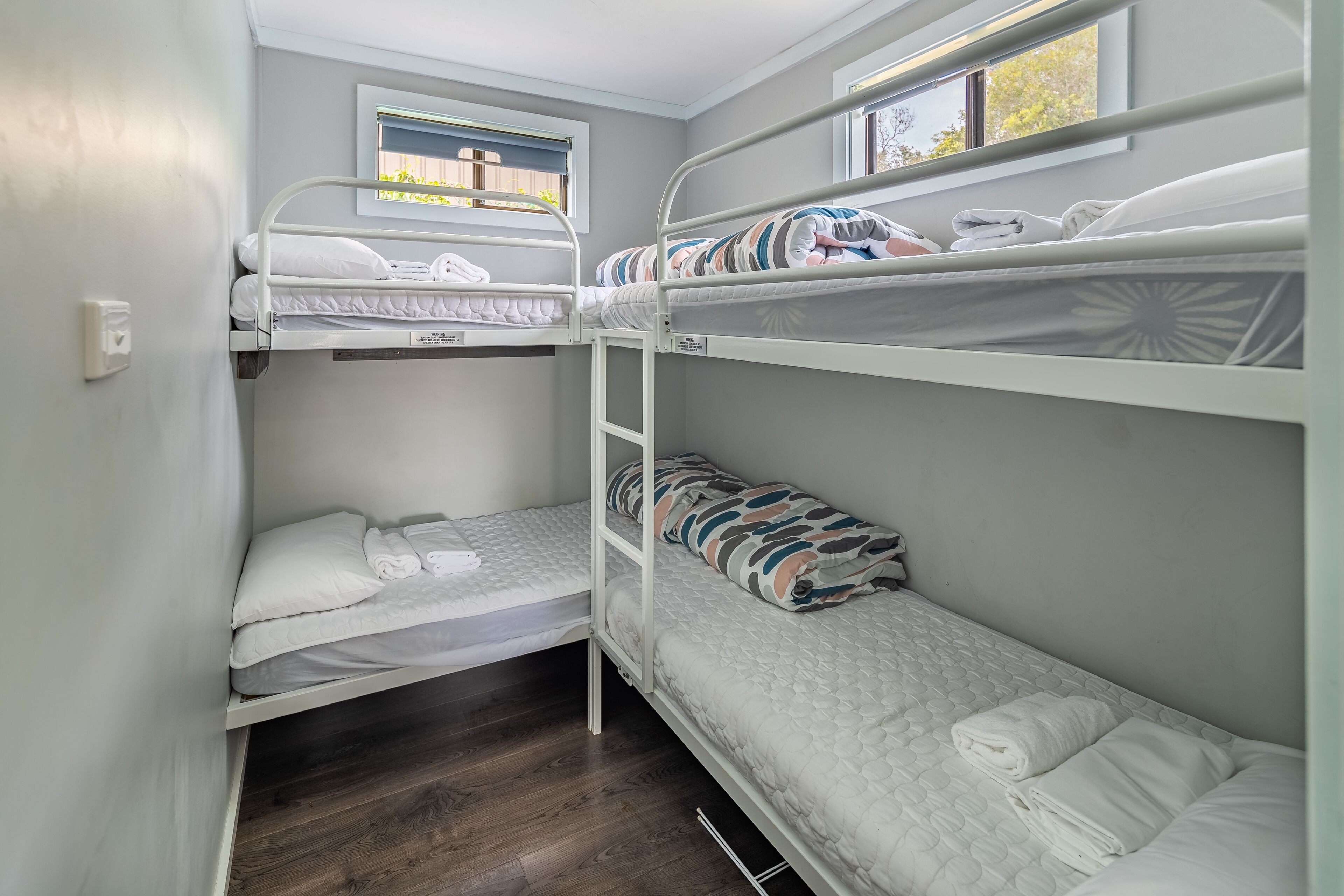 Dormitorio con literas, una ventana y suelo de madera.