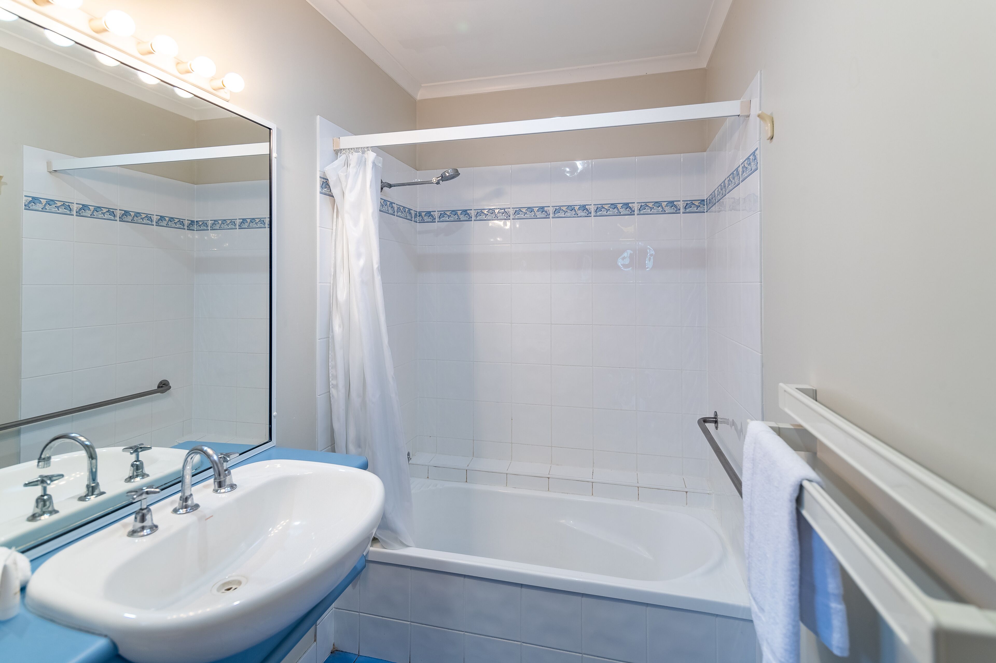 Een badkamer met een wit wastafel, een bad en een douche.