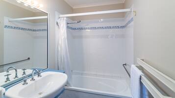 Een badkamer met een wit wastafel, een bad en een douche.