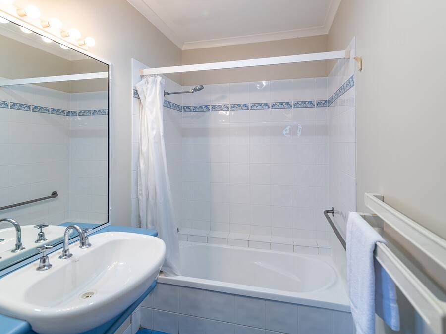 Een badkamer met een wit wastafel, een bad en een douche.