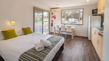 A hotel room with a bed, a desk, and a kitchenette.