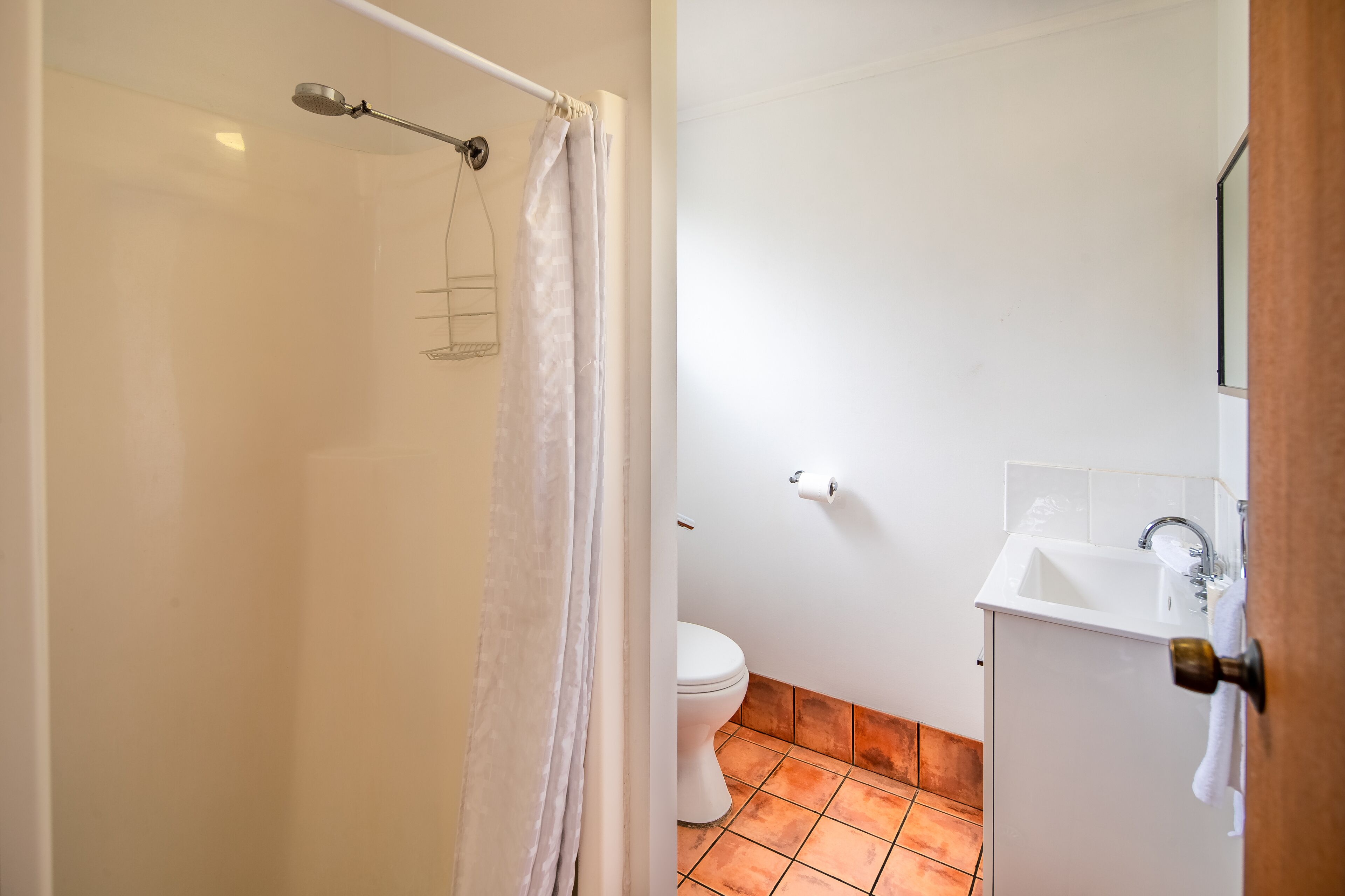 A bathroom with a shower, toilet, and sink.
