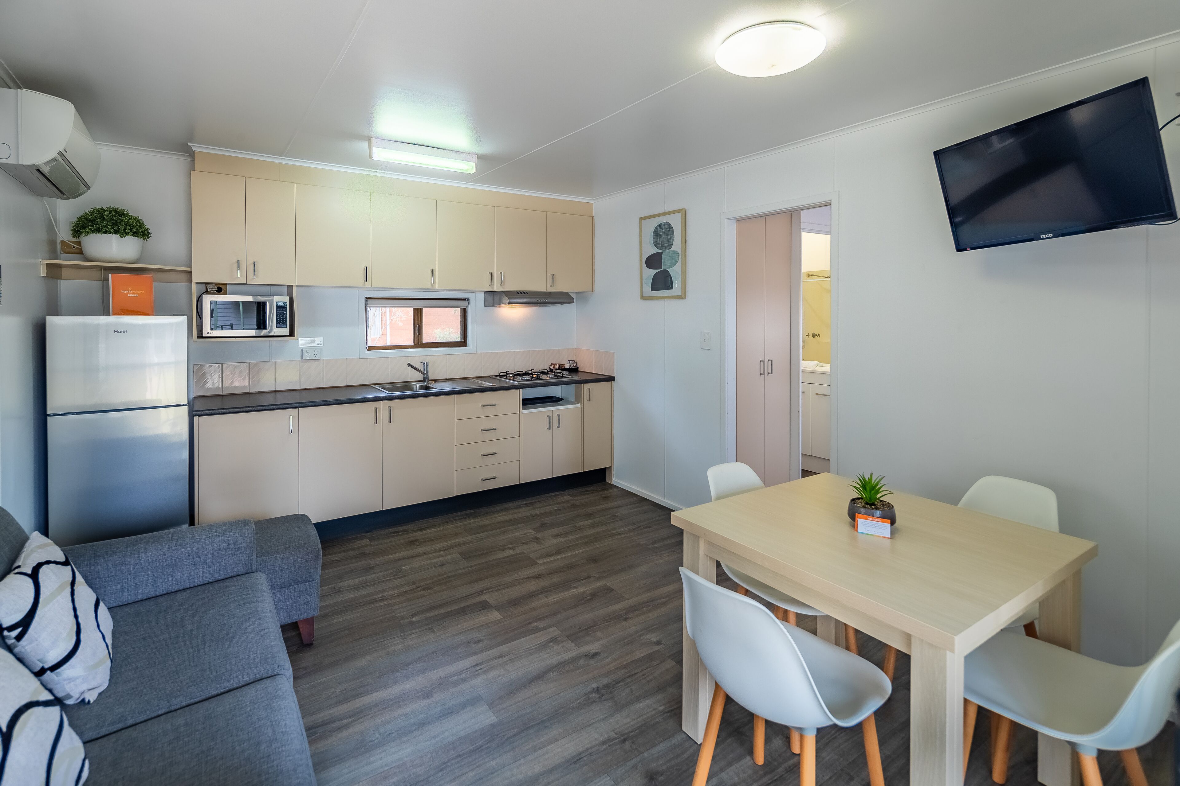 Een moderne keuken met een eethoek, een flatscreen televisie en een bank.