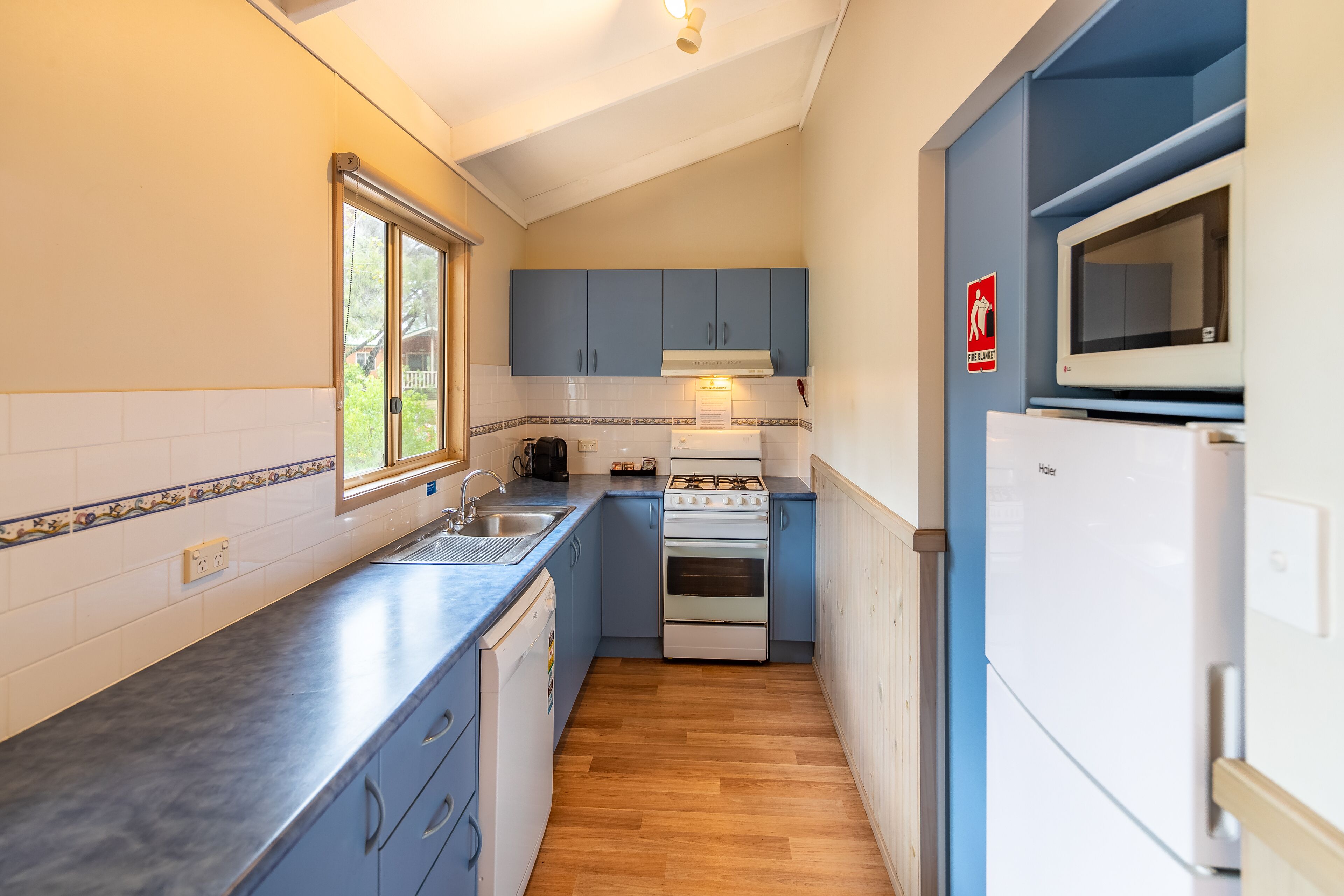 A compact kitchen with a gas stove, oven, microwave, and a sink.