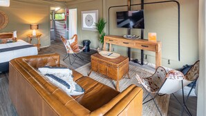 A cozy room with a bed, leather sofa, and a TV mounted on the wall. - NRMA Broulee Holiday Park (Broulee)