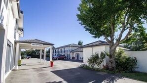 A reception area with a clear sky, a parking lot, and a building with a sign.