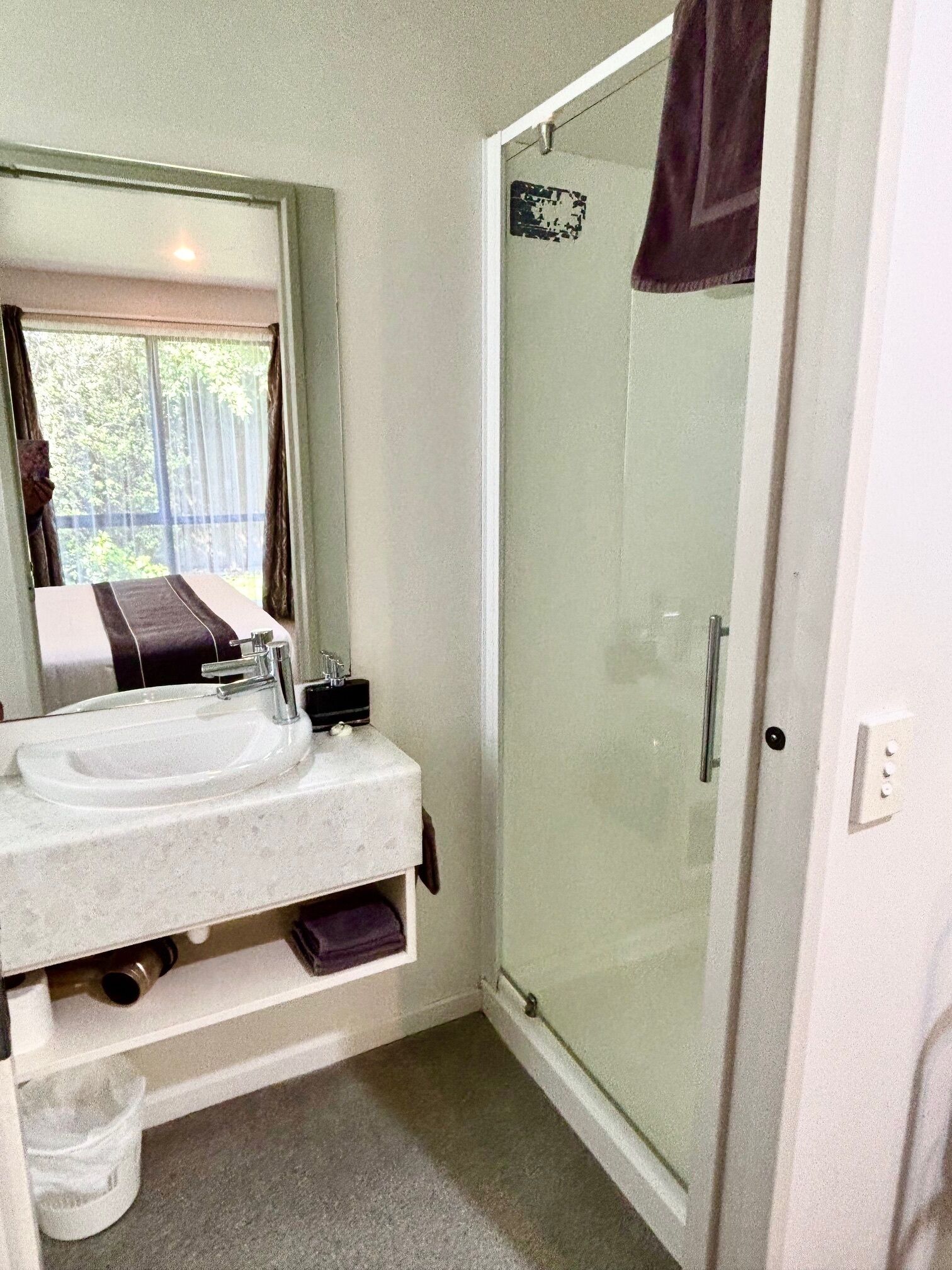 A bathroom with a sink, mirror, and shower.