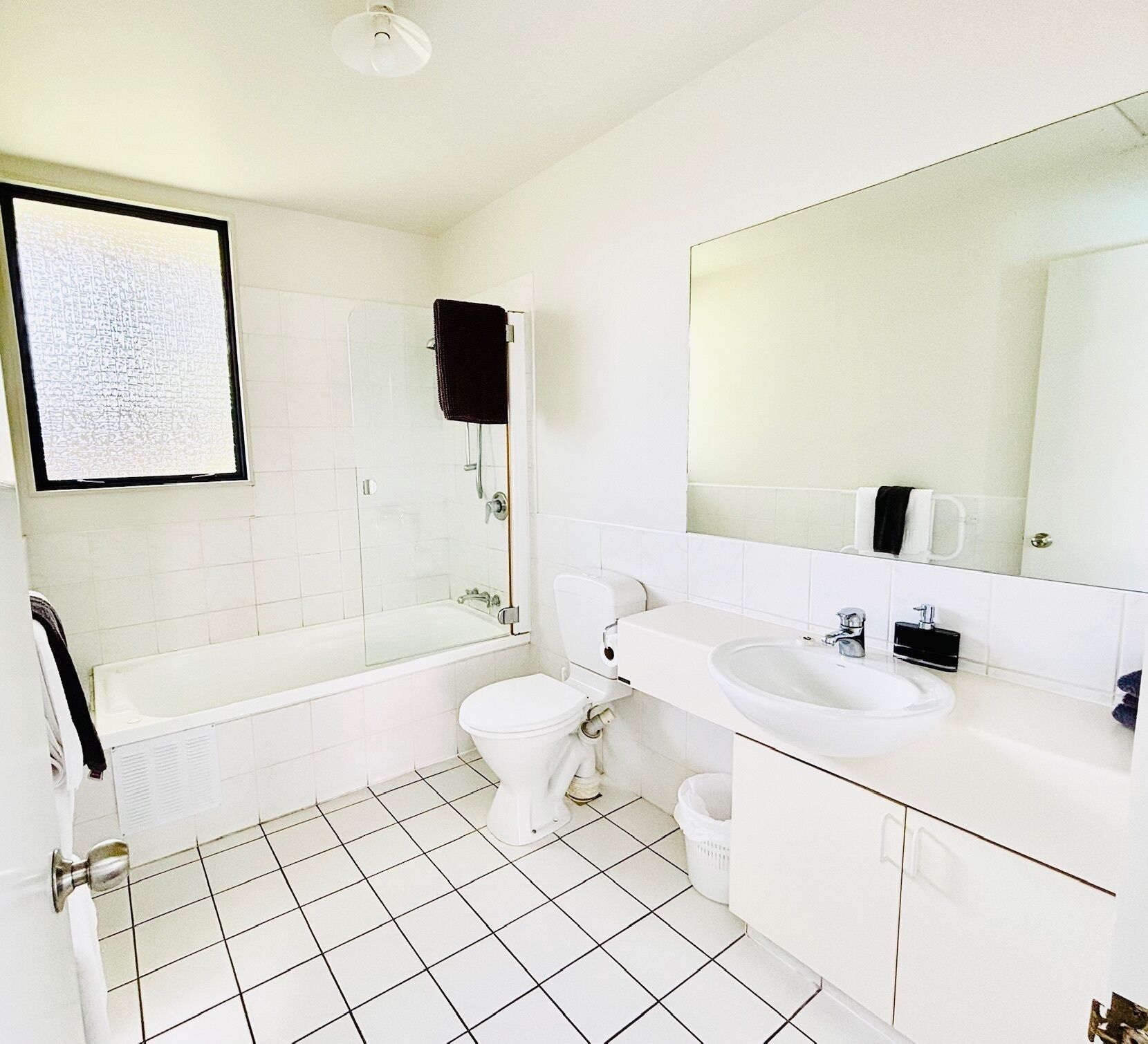 A bathroom with a bathtub, toilet, sink, and a large mirror.