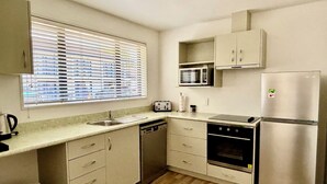 Una cocina compacta con lavamanos, microondas, tostadora y refrigerador.