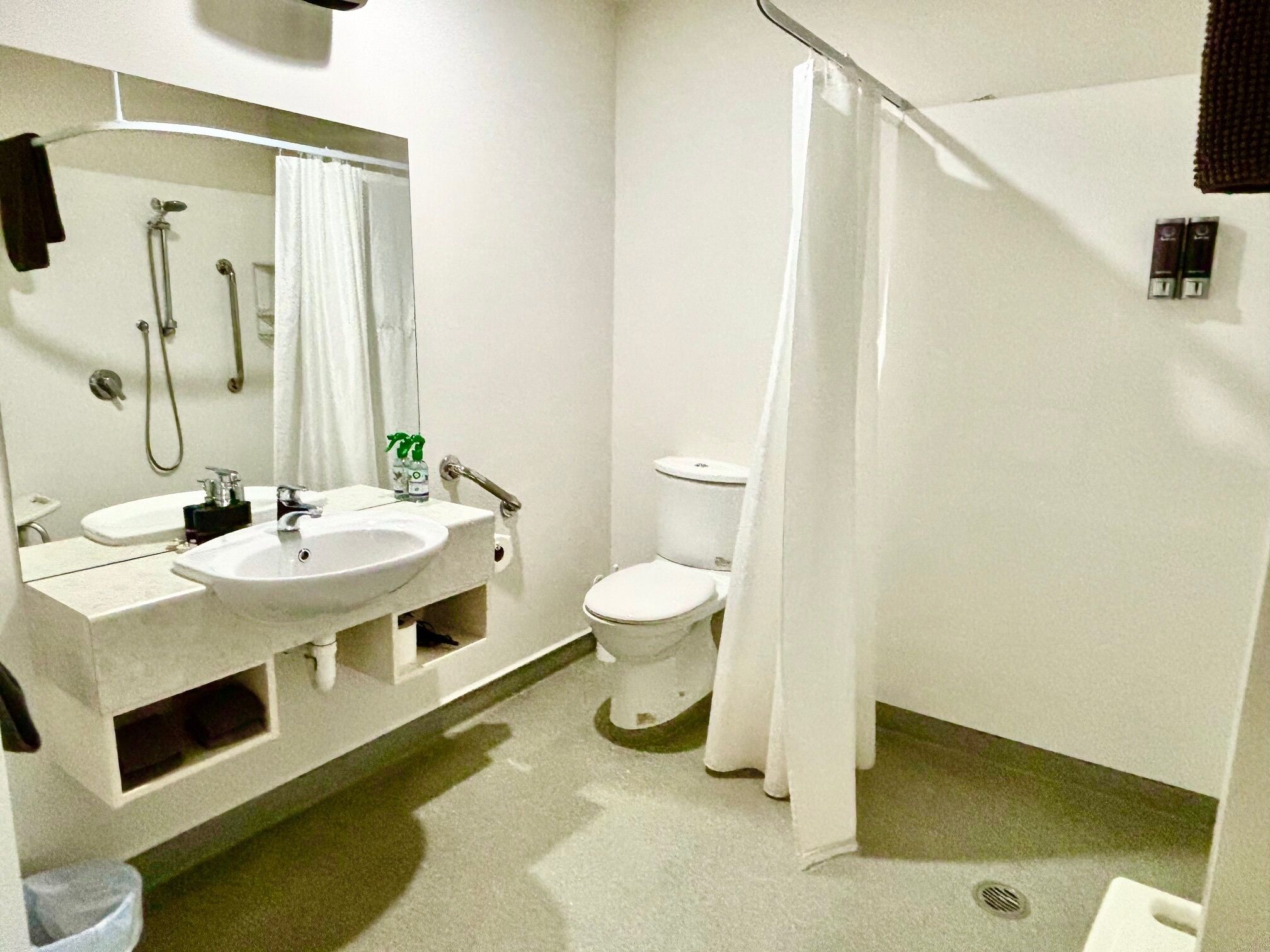 Un baño pequeño y limpio con lavamanos, espejo, inodoro y cortina de ducha.