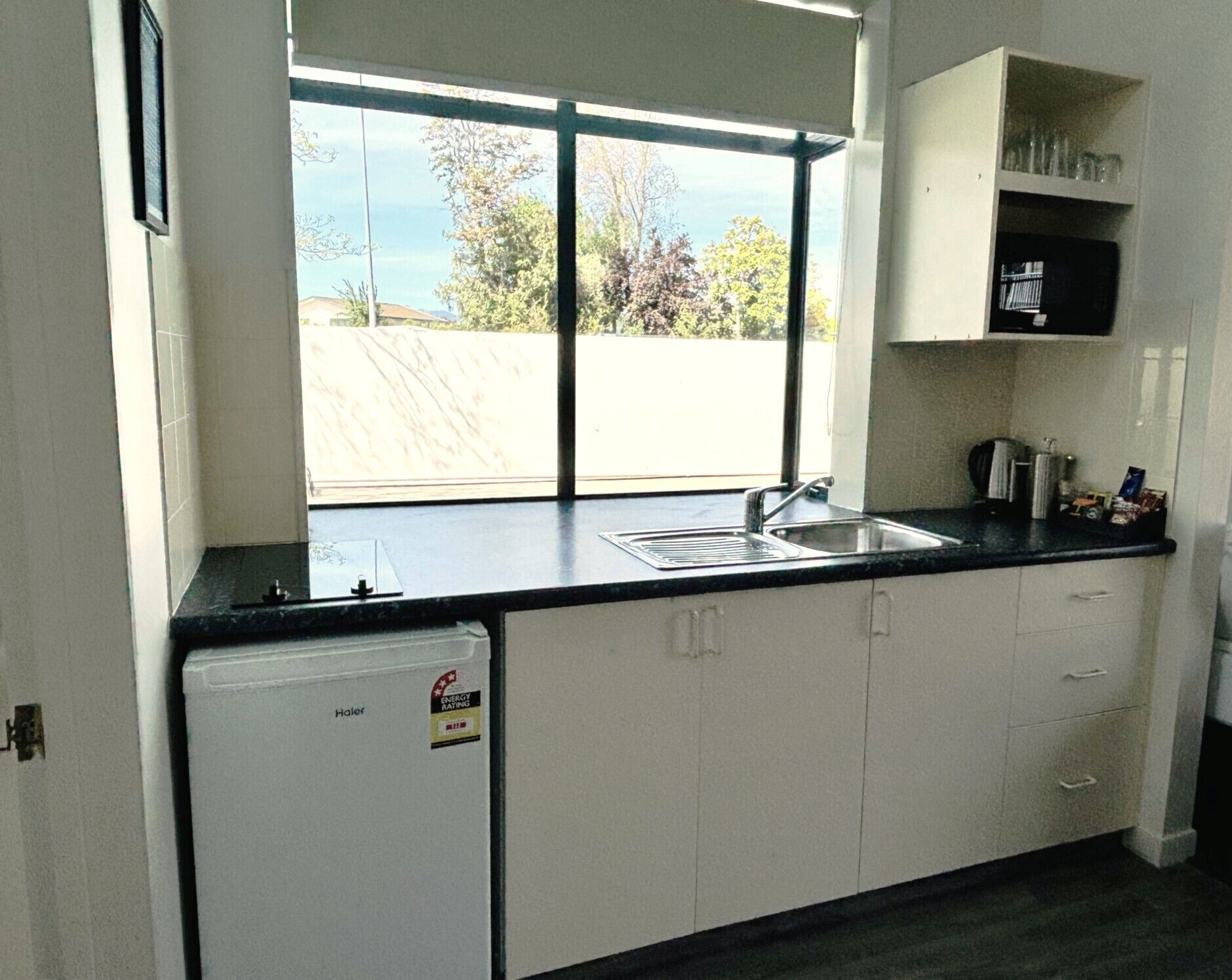 Una cocina con ventana, refrigerador y lavamanos.