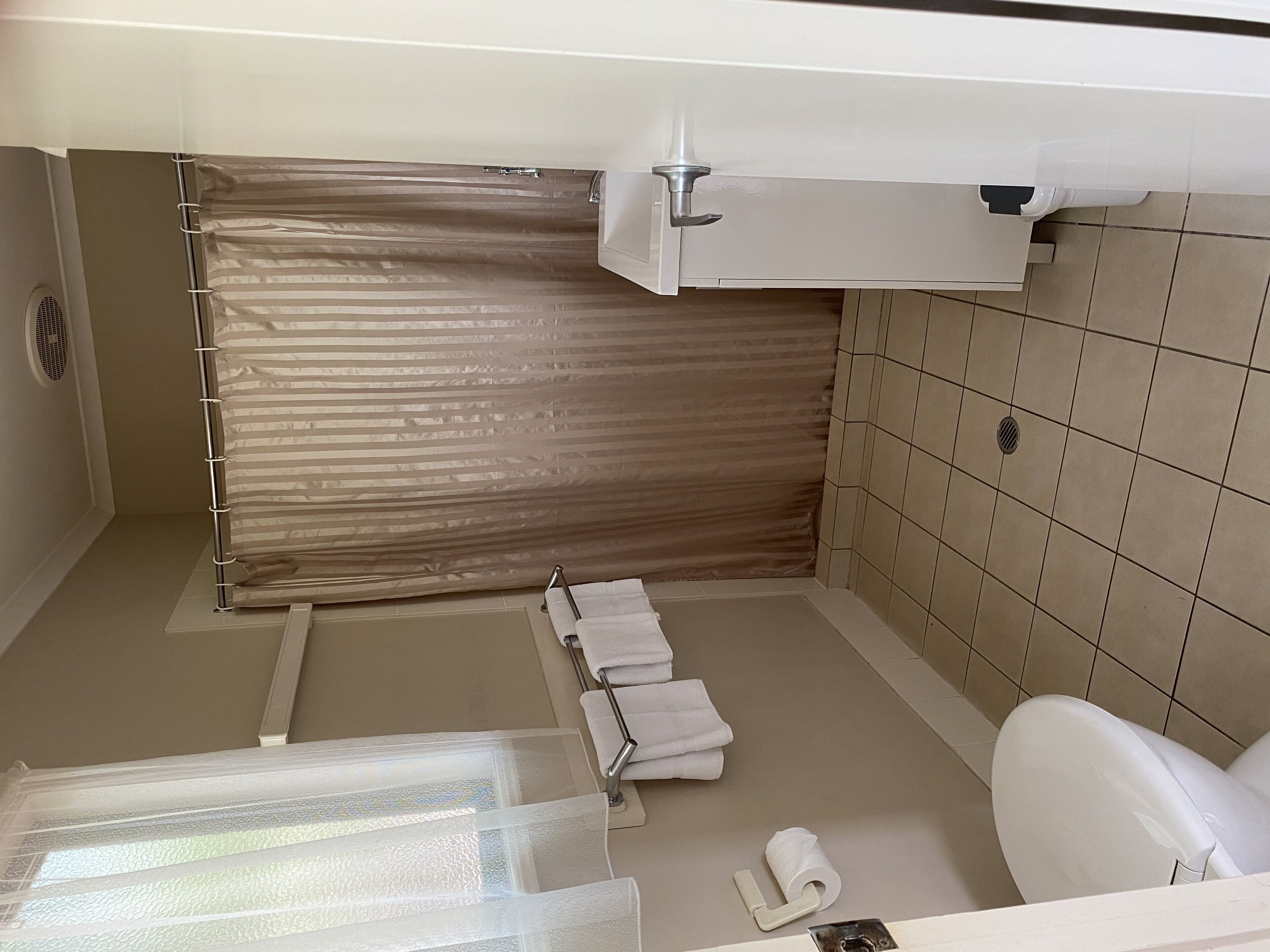 Un baño con cortina de ducha, inodoro y barra para toallas.