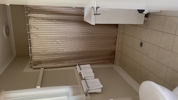 Un baño con cortina de ducha, inodoro y barra para toallas.
