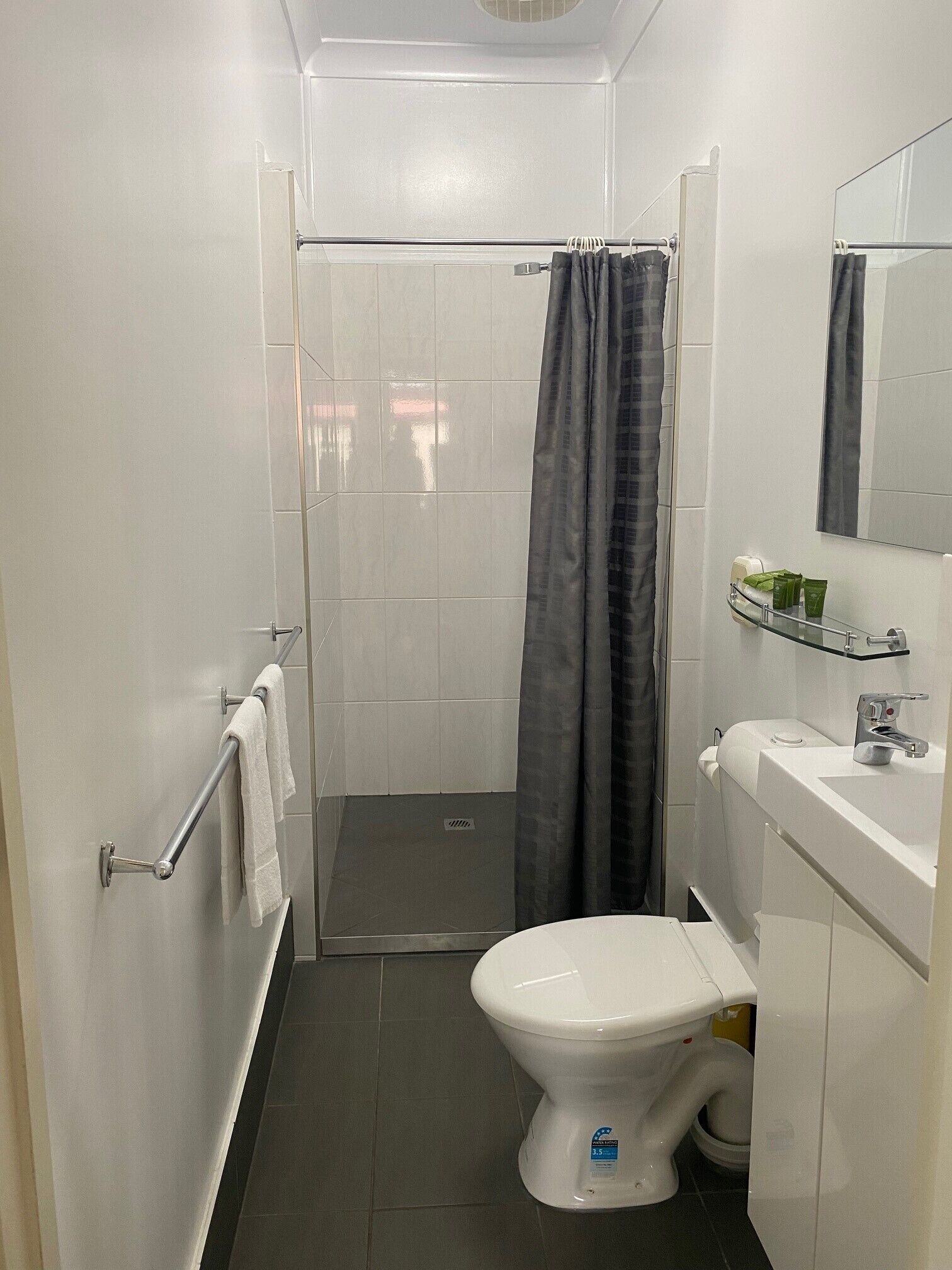 A compact bathroom with a shower, toilet, and a small sink area.