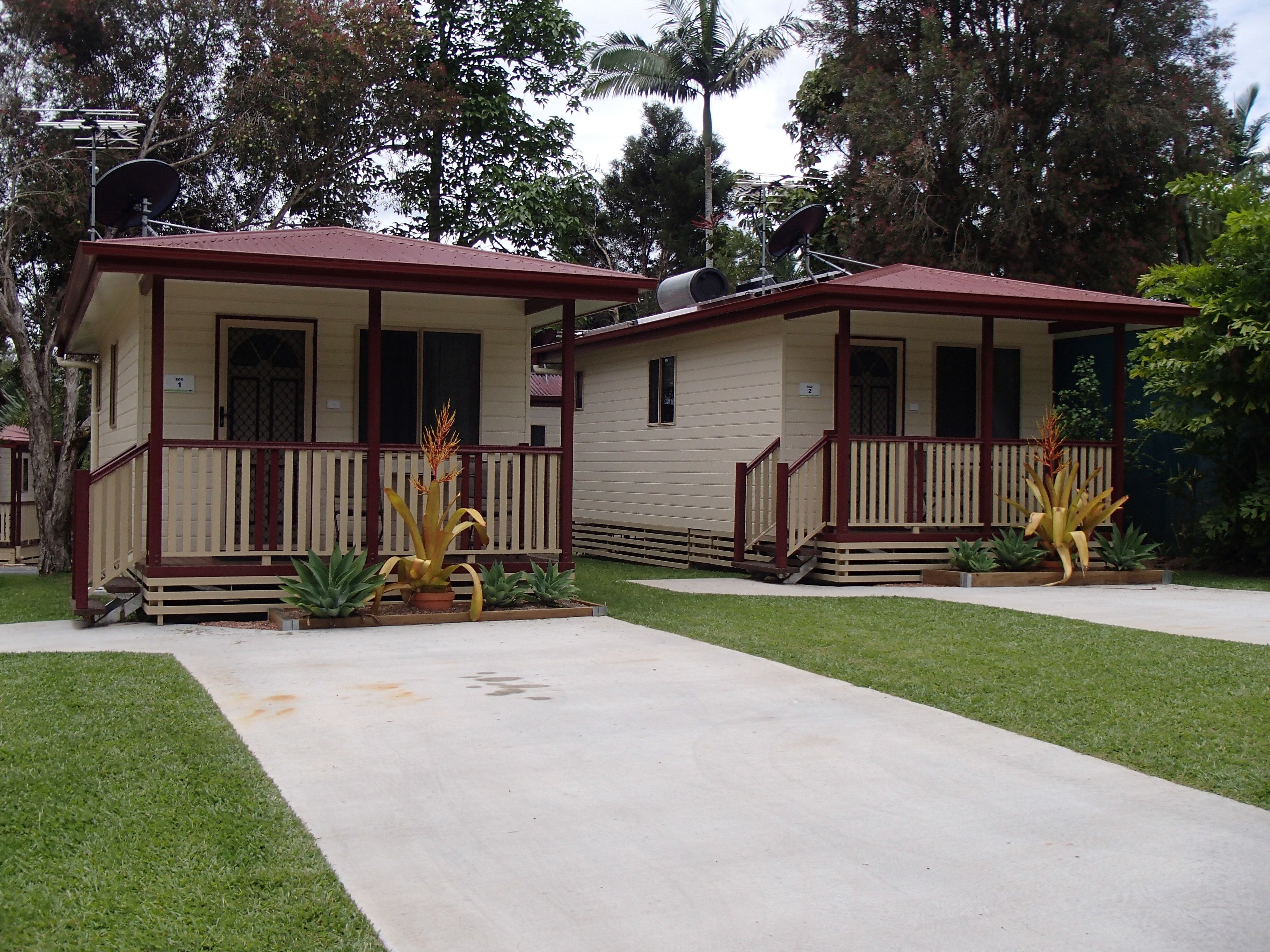 Two small, single-story buildings with a porch and a small garden area in front.