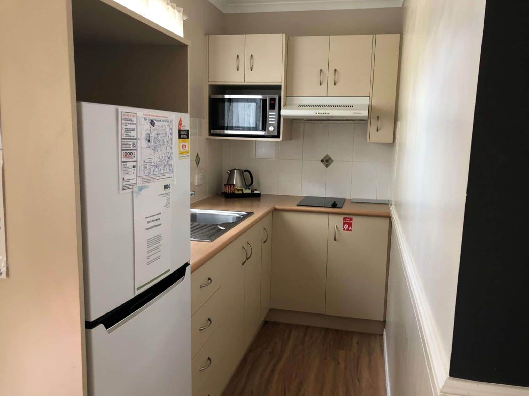 A compact kitchen with a refrigerator, microwave, sink, and cabinets.