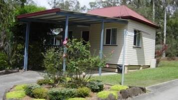 A small, single-story house with a red roof and a covered porch.