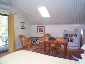 Une pièce confortable avec un lit, une table à manger et des chaises, une bibliothèque et une fenêtre avec des rideaux.