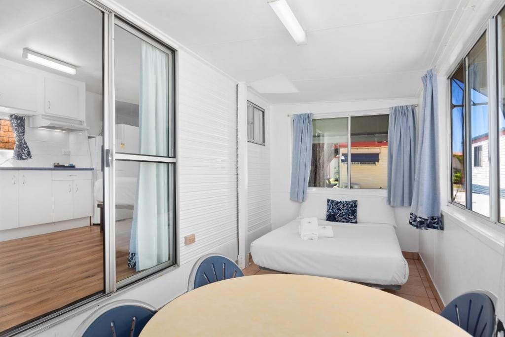Una camera d'albergo compatta con un letto, un tavolo da pranzo e angolo cottura.