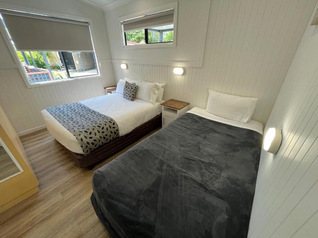 Une chambre avec deux lits, une fenêtre et une table de chevet.