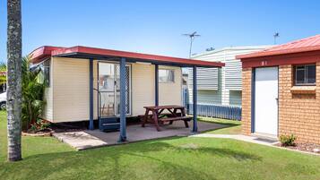 A mobile home with a covered patio, a picnic table, and a small garden area.