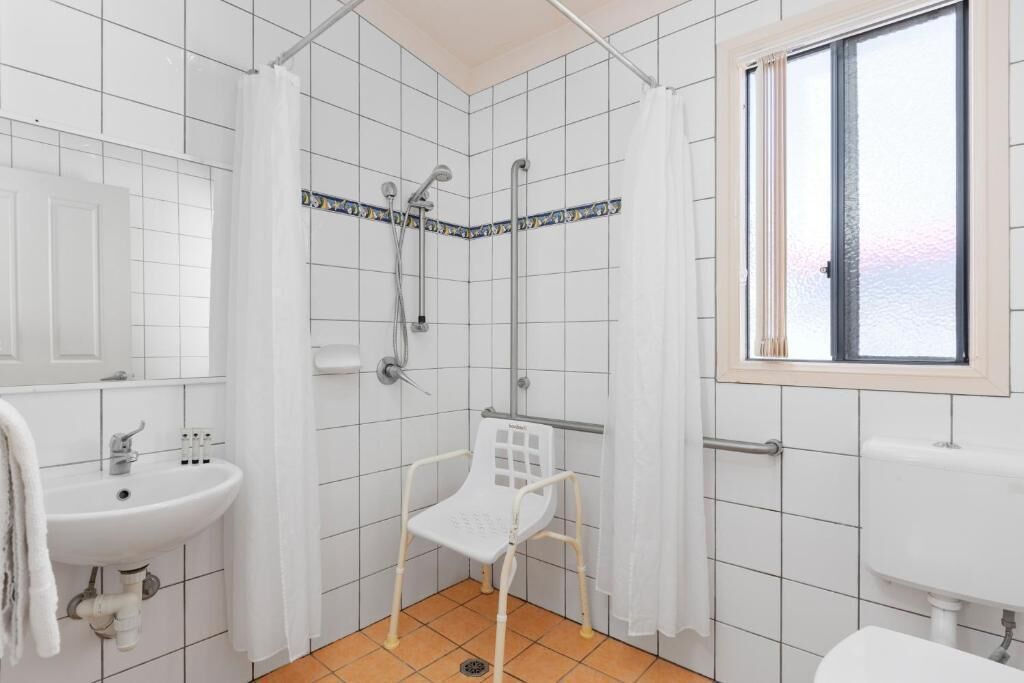 A bathroom with a shower, a sink, and a window.