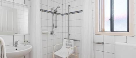 A bathroom with a shower, a sink, and a window.