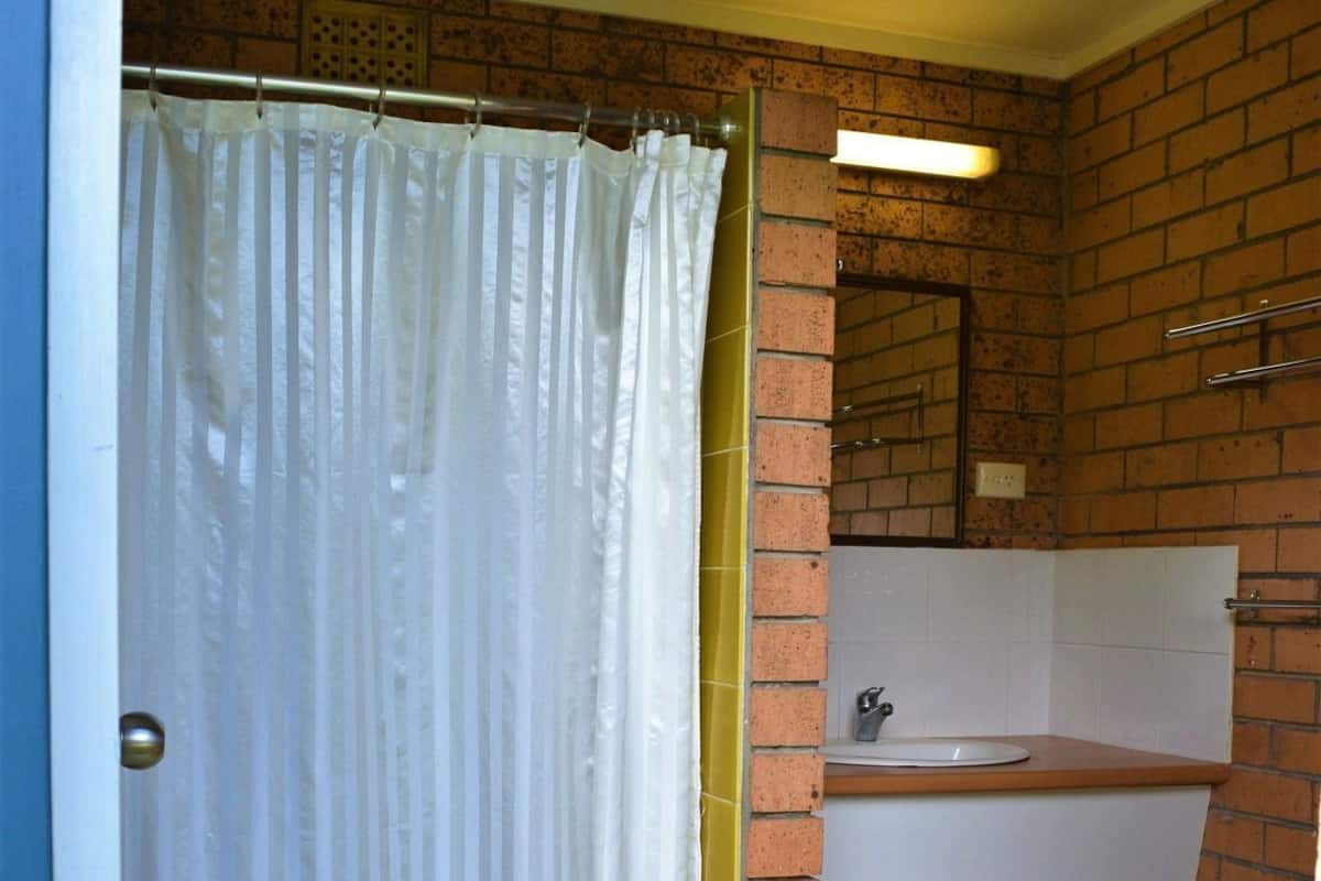 A bathroom with a shower curtain, a sink, and a mirror.