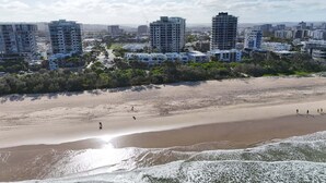 Un paisaje urbano costero con rascacielos, una playa arenosa y un cielo despejado.
