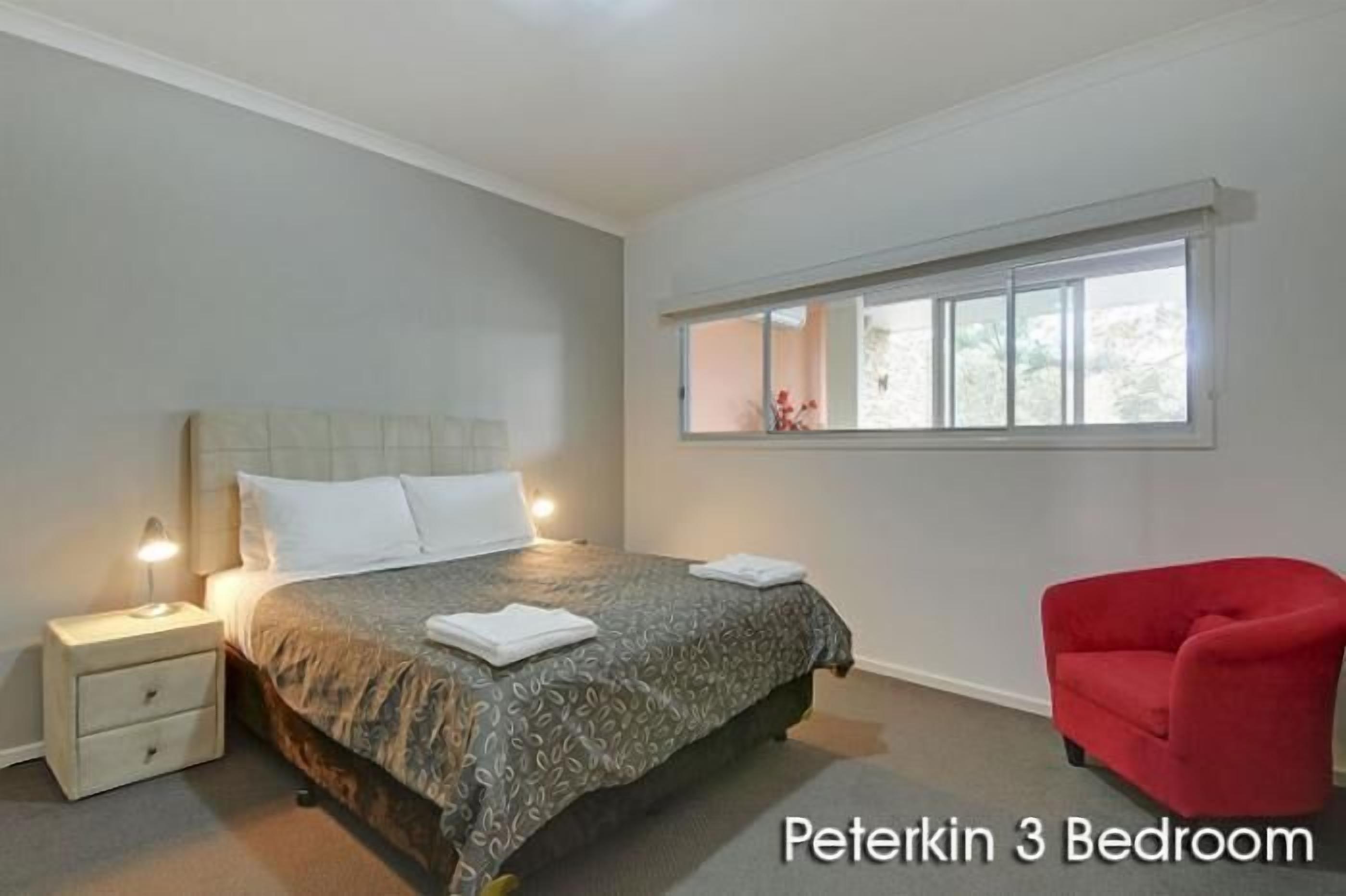 Une chambre à coucher avec un lit, une table de chevet et une fenêtre.