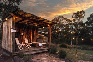 Una cabaña de madera rústica con un porche, dos sillones de descanso y una mesita.