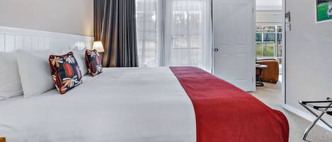 Habitación de hotel con cama, una manta roja y vistas al exterior a través de una puerta.