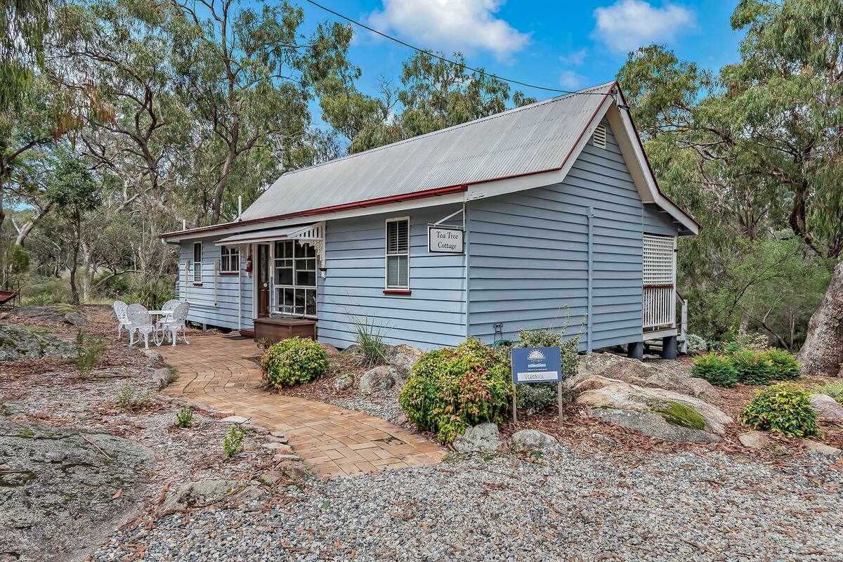 A small, single-story building with a porch and a sign indicating it is a Tea Tree Cottage.