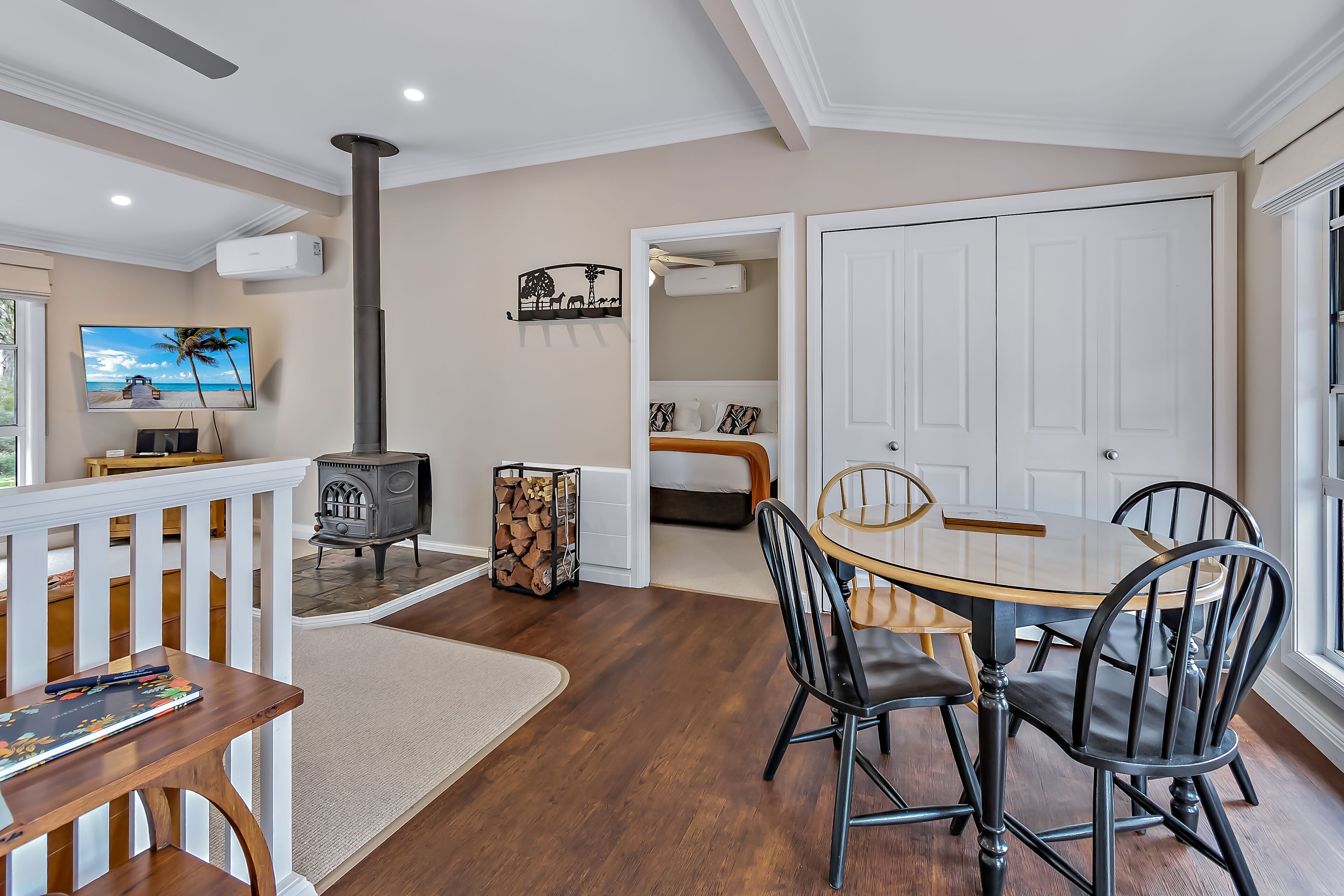 A dining area with a round table and chairs, a fireplace, and a television on the wall.