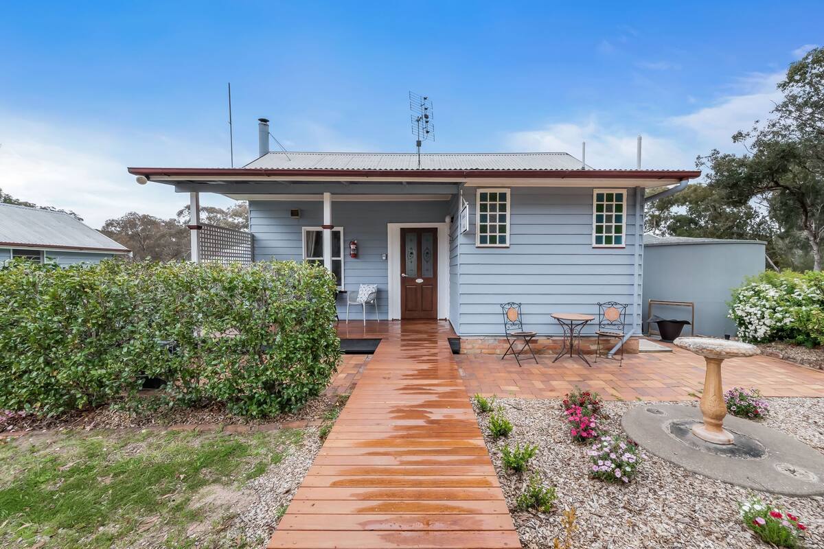 A house with a front porch, a small garden, and a pathway leading to the entrance.