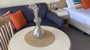 Une chambre d’hôtel avec une table ronde, un canapé, un lit et un tableau au mur.
