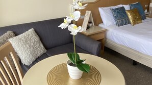 Une chambre d’hôtel avec un lit, un canapé, une petite table avec une plante et un tableau au mur.