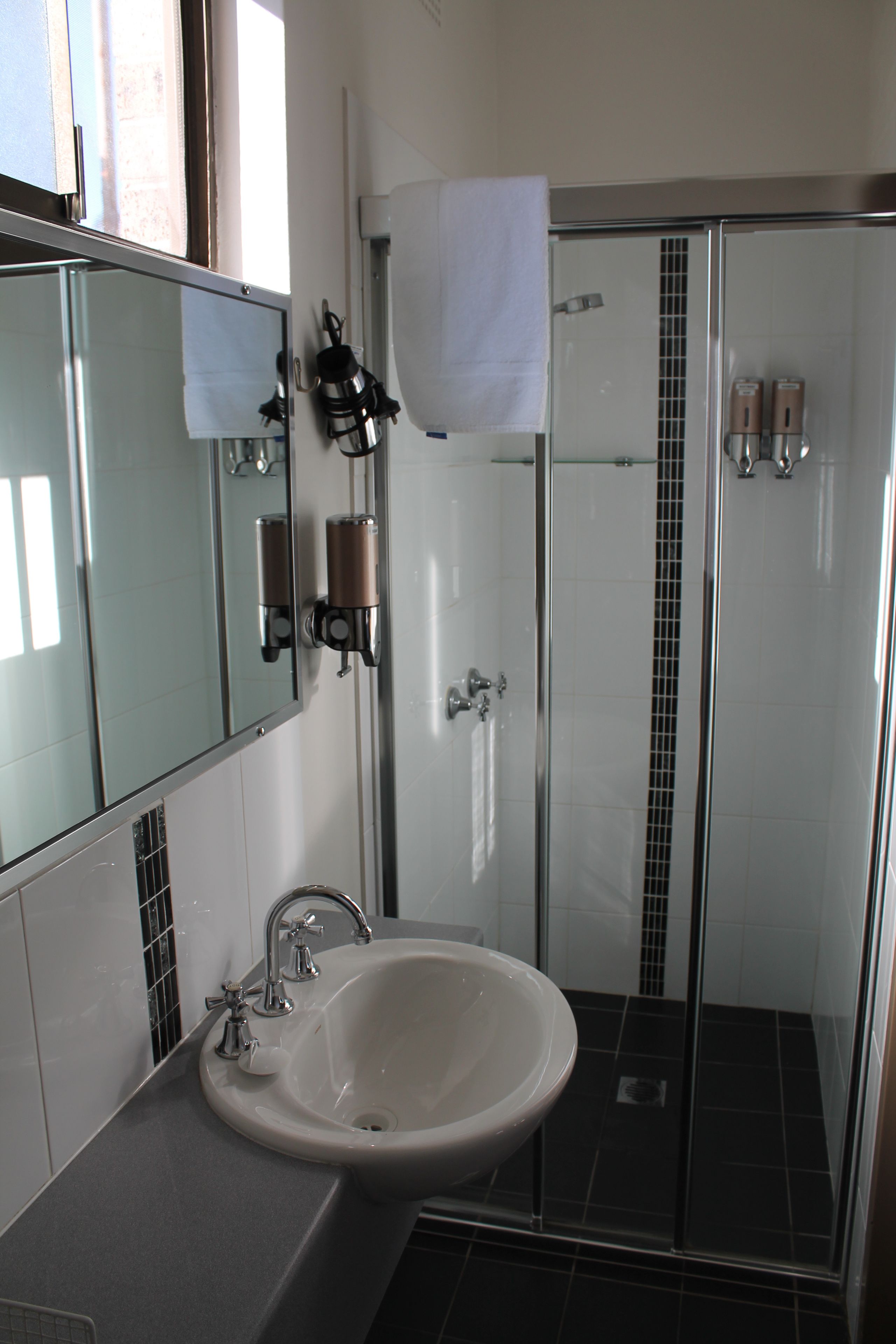A modern bathroom with a sink, mirror, and shower.