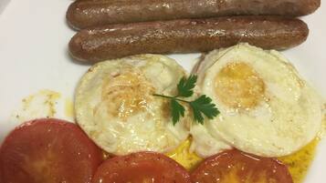 A plate with sausages, eggs, and tomatoes.