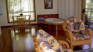 Una habitación con piso de madera, una mesa redonda con sillas, un sofá y una bañera.