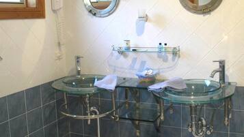 A bathroom with two glass sinks, a toilet, and a window.