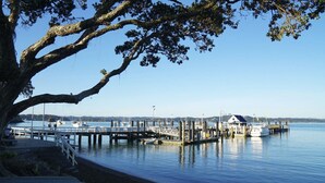 Un muelle frente al agua con barcos, un pequeño edificio y un árbol.