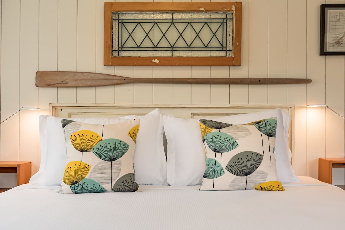 Un lit avec une literie blanche et des coussins décoratifs ornés de motifs floraux abstraits.
