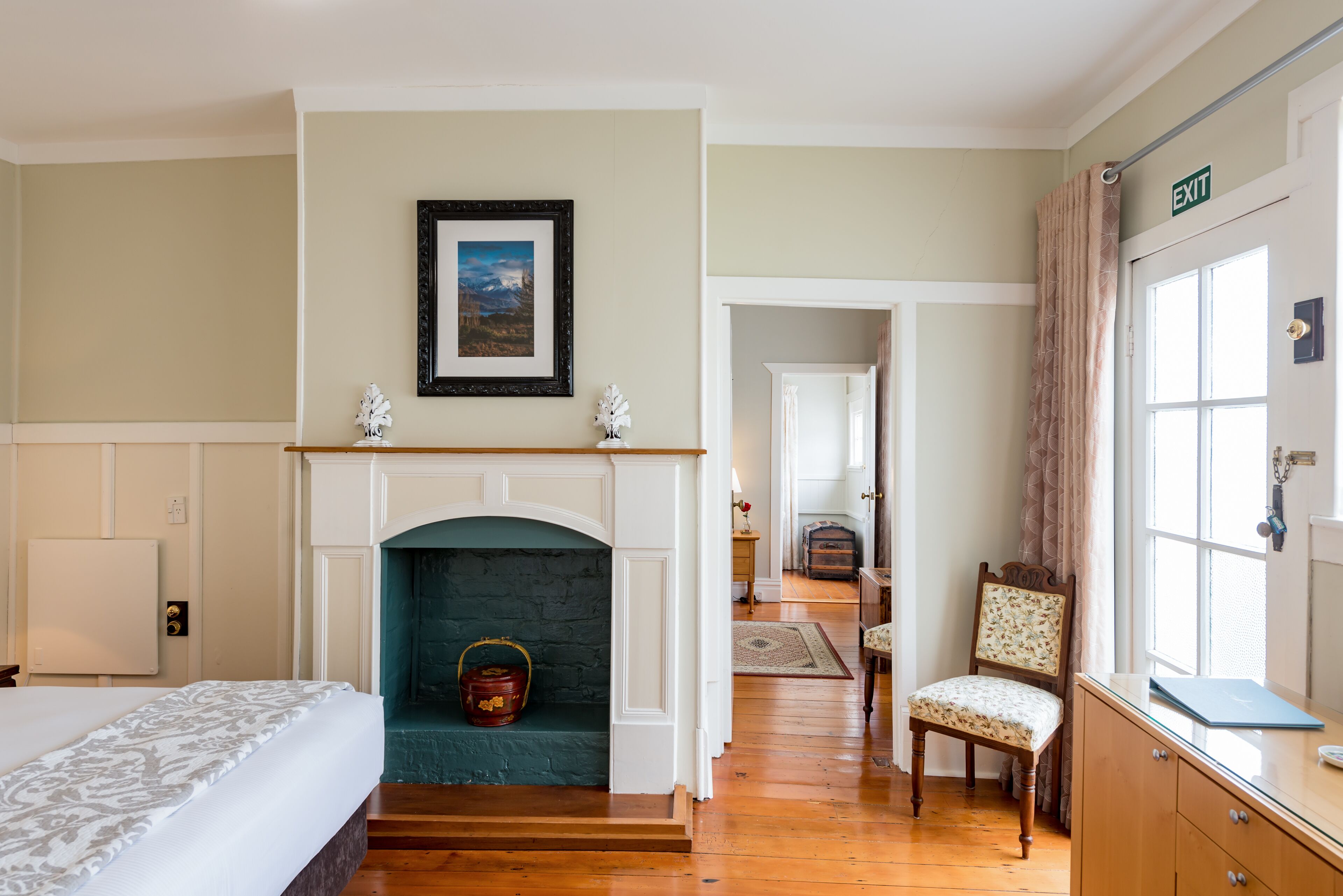 A hotel room with a fireplace, a bed, a chair, and a desk.