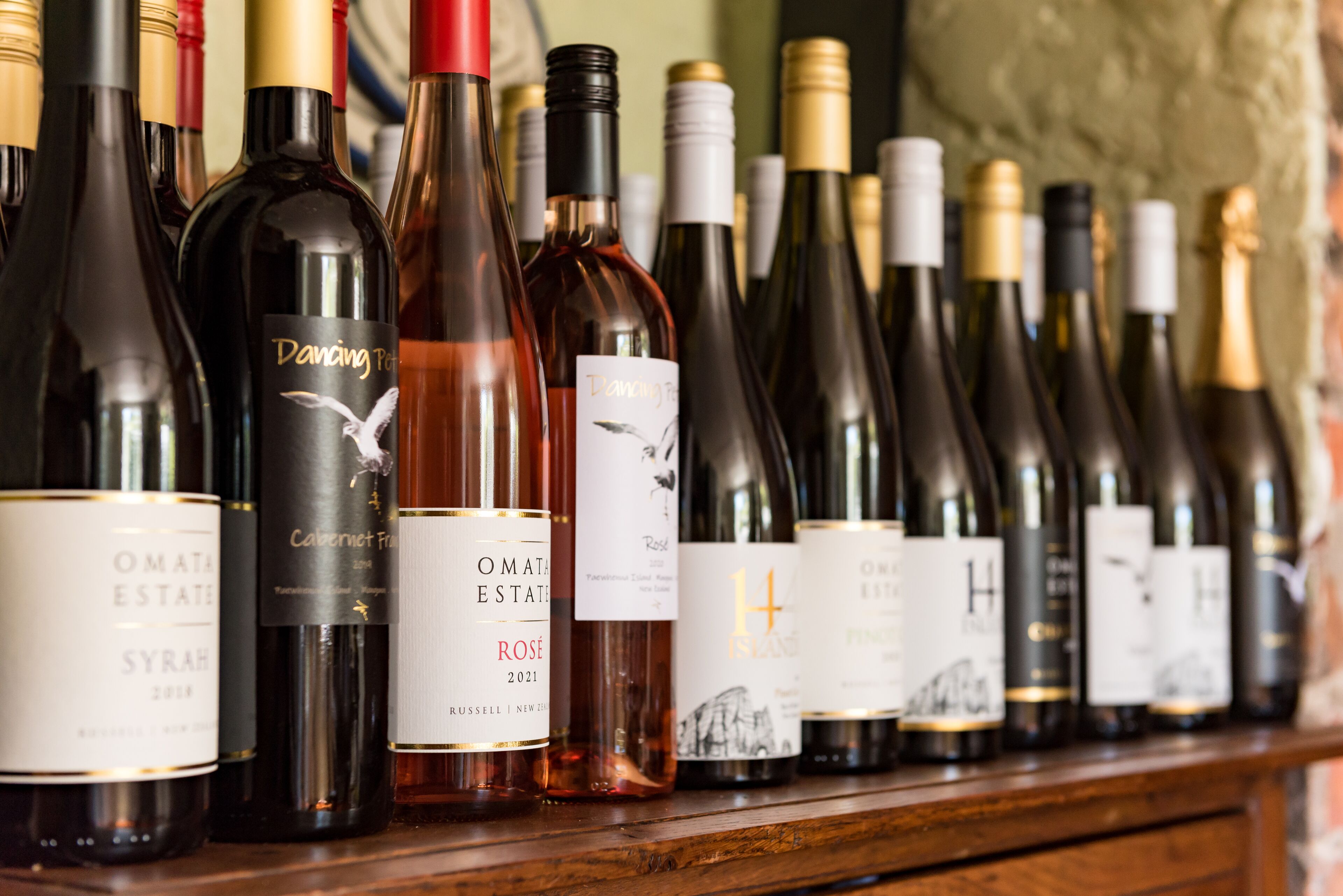 A row of wine bottles on a wooden shelf.