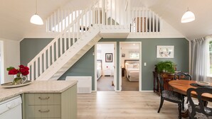 Una cocina amplia con una escalera blanca que sube a un dormitorio tipo loft.