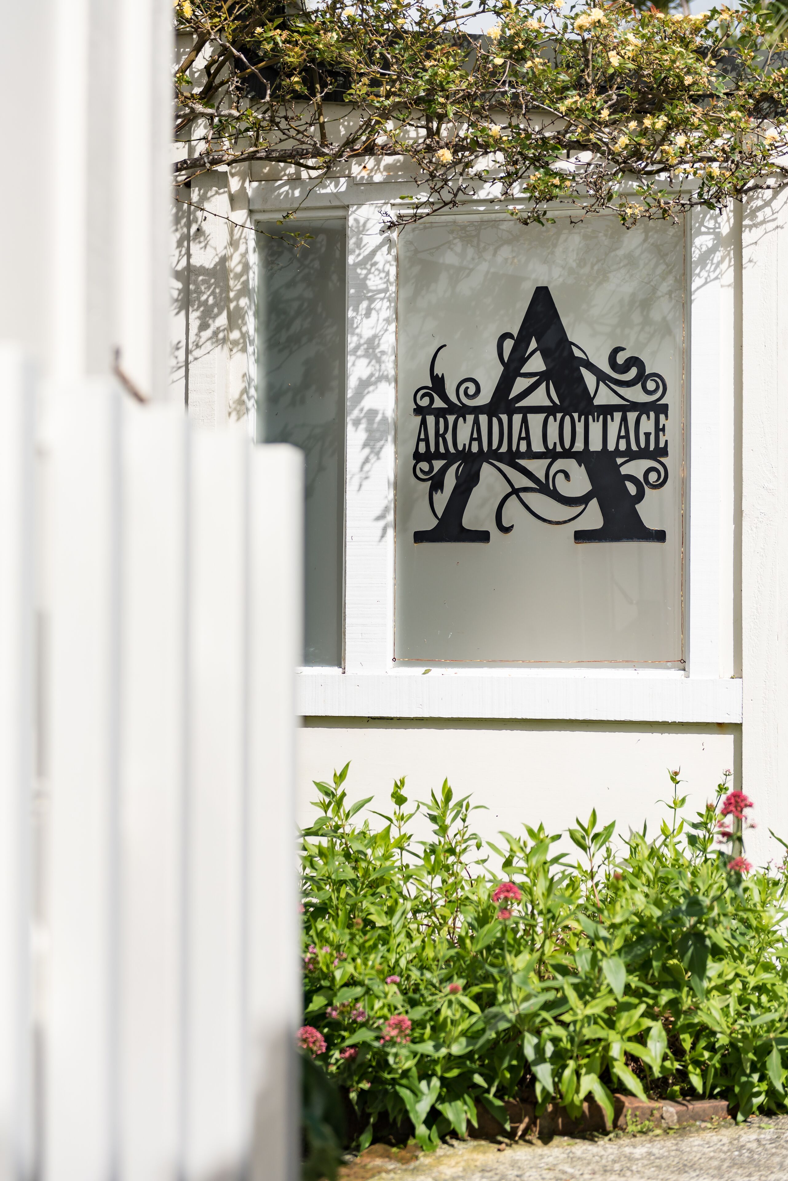A sign with the text "Arcadia Cottage" on a white wall.