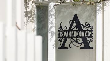 A sign with the text "Arcadia Cottage" on a white wall.
