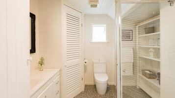 A compact bathroom with a toilet, a small window, and a vanity with drawers.