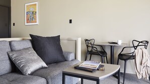 A modern living room with a grey sofa, a coffee table with a book, a small table with a white cup, and black chairs. - Ridgemill Escape (Broadwater)